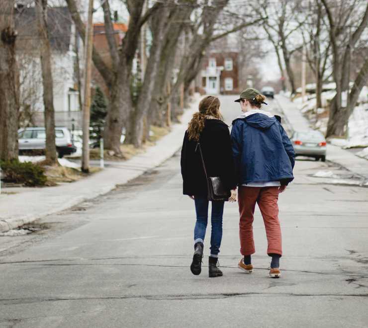 Teen couple holding hands walking down the street in the winter